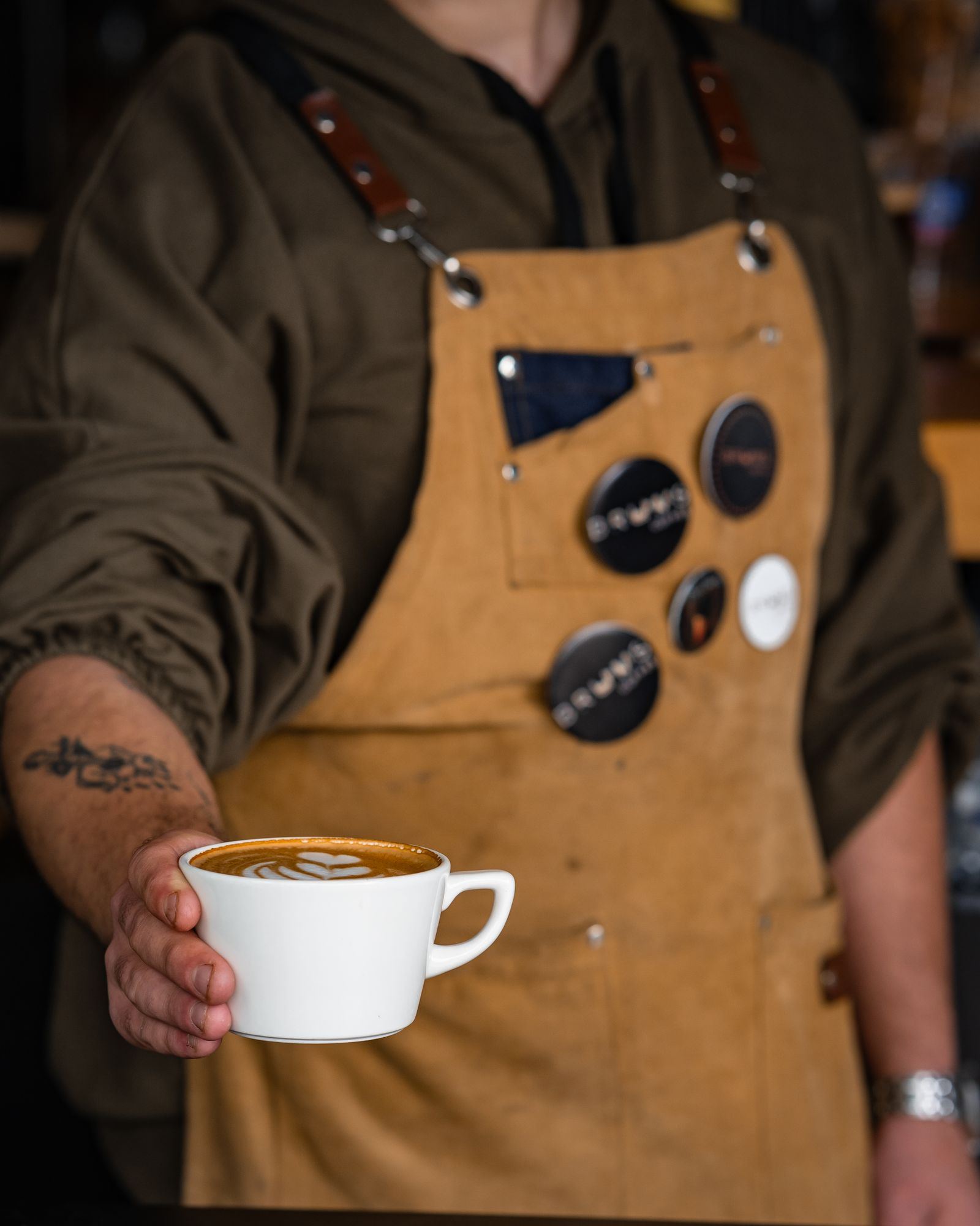 エプロン姿でコーヒーを手にする店主