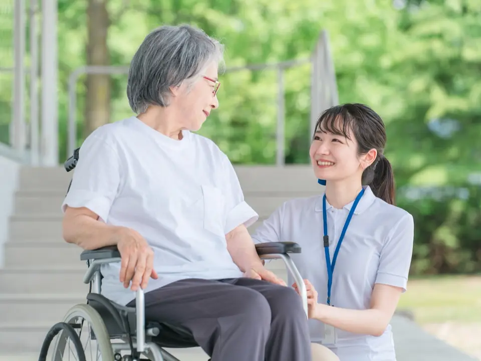 車いすの高齢の方と笑顔で話す看護師