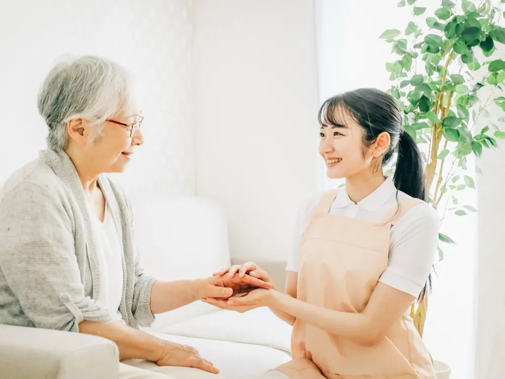 高齢の方の手を取り笑顔で話すスタッフ